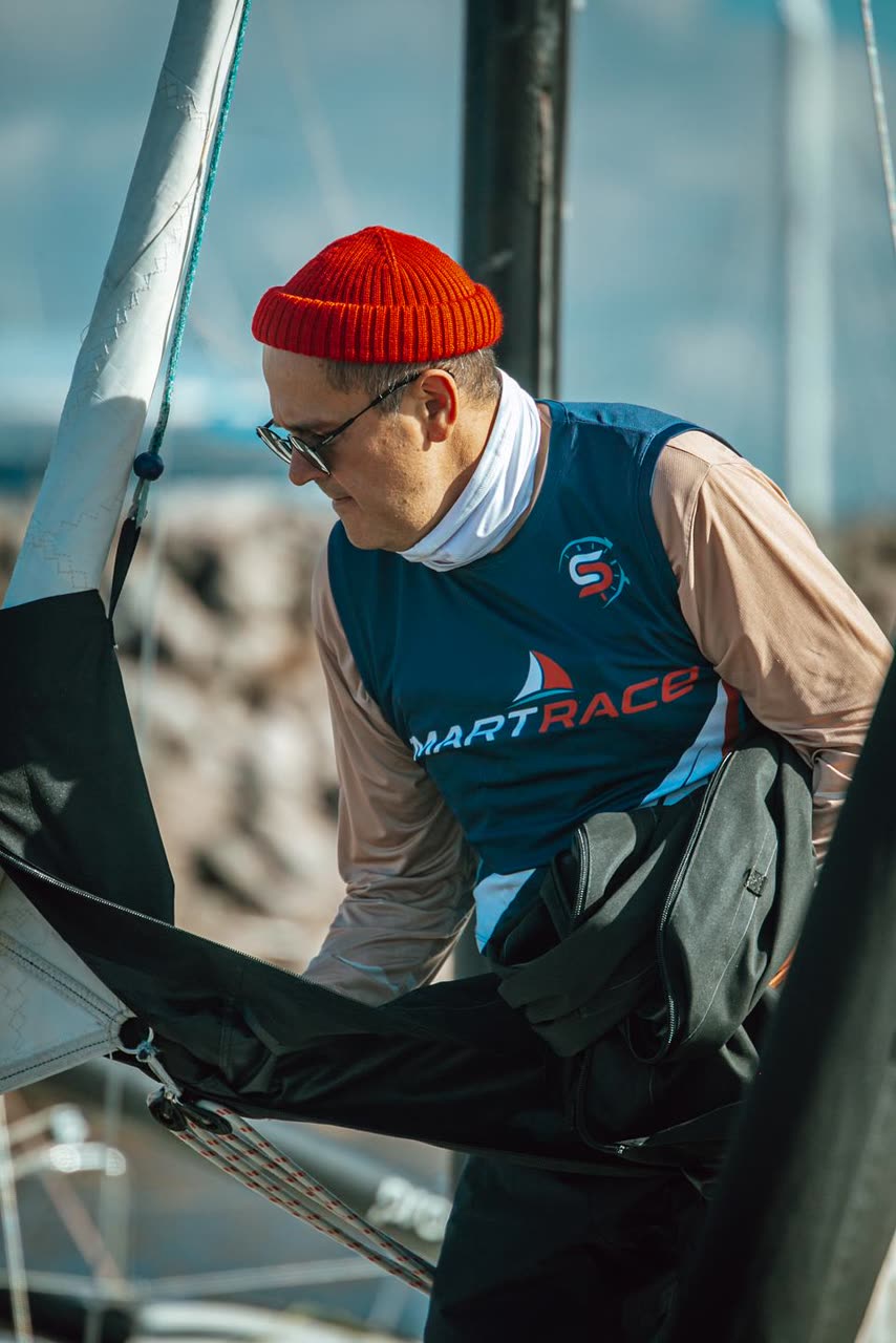 Сергей в форме Smart Race готовит паруса на пирсе